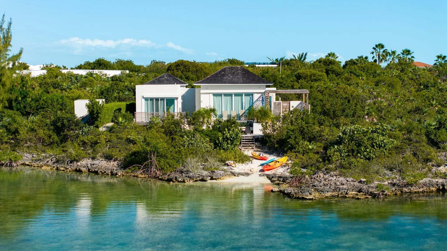 Vista Cove above the water in Chalk Sound, with kayaks at the shoreline
